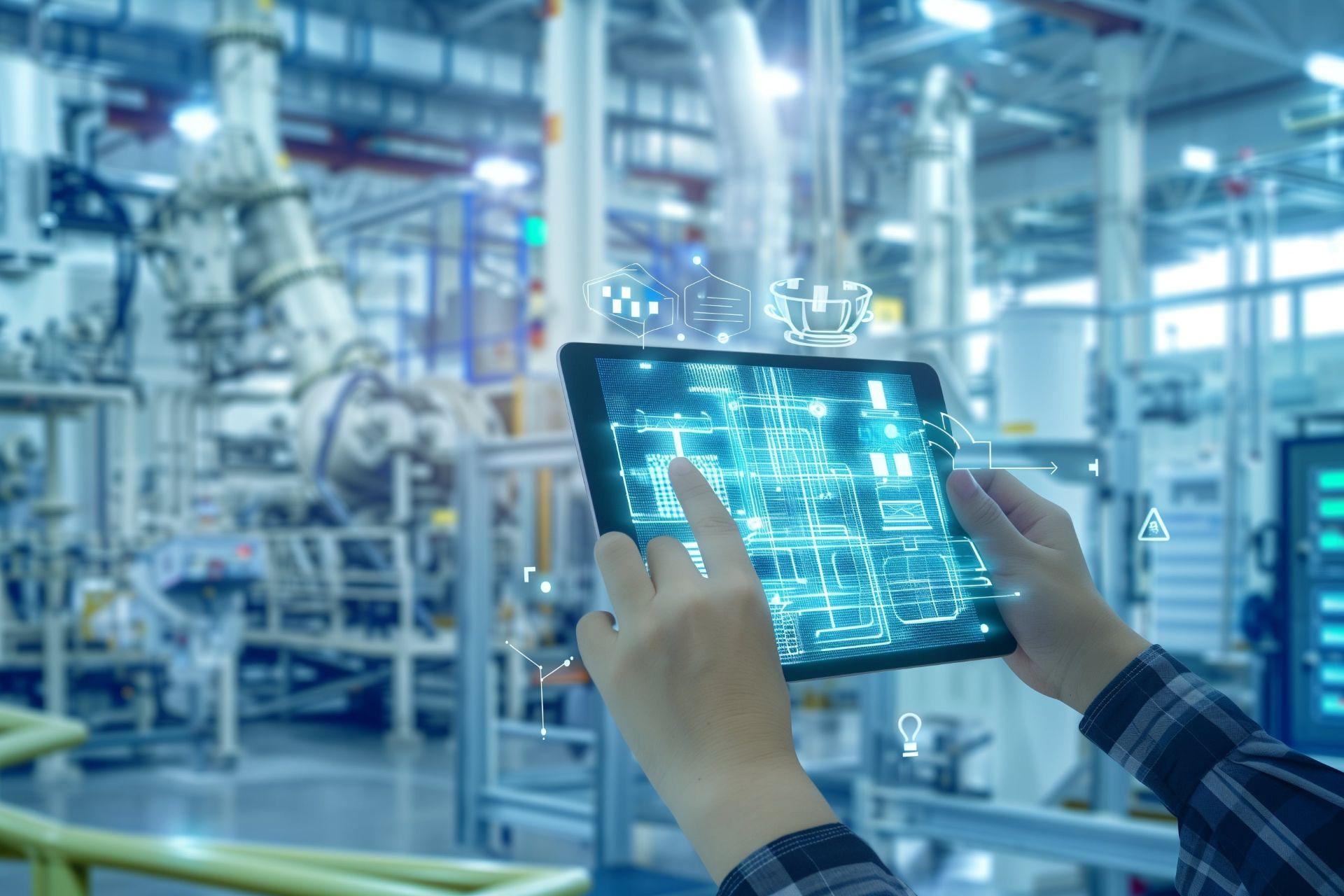 Mitarbeiter nutzt Tablet zur Ăśberwachung digitaler Produktionsdaten in einer vernetzten Industrieumgebung